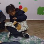 Crianças observam os animais nas mãos da educadora em atividade de Bioterapia.