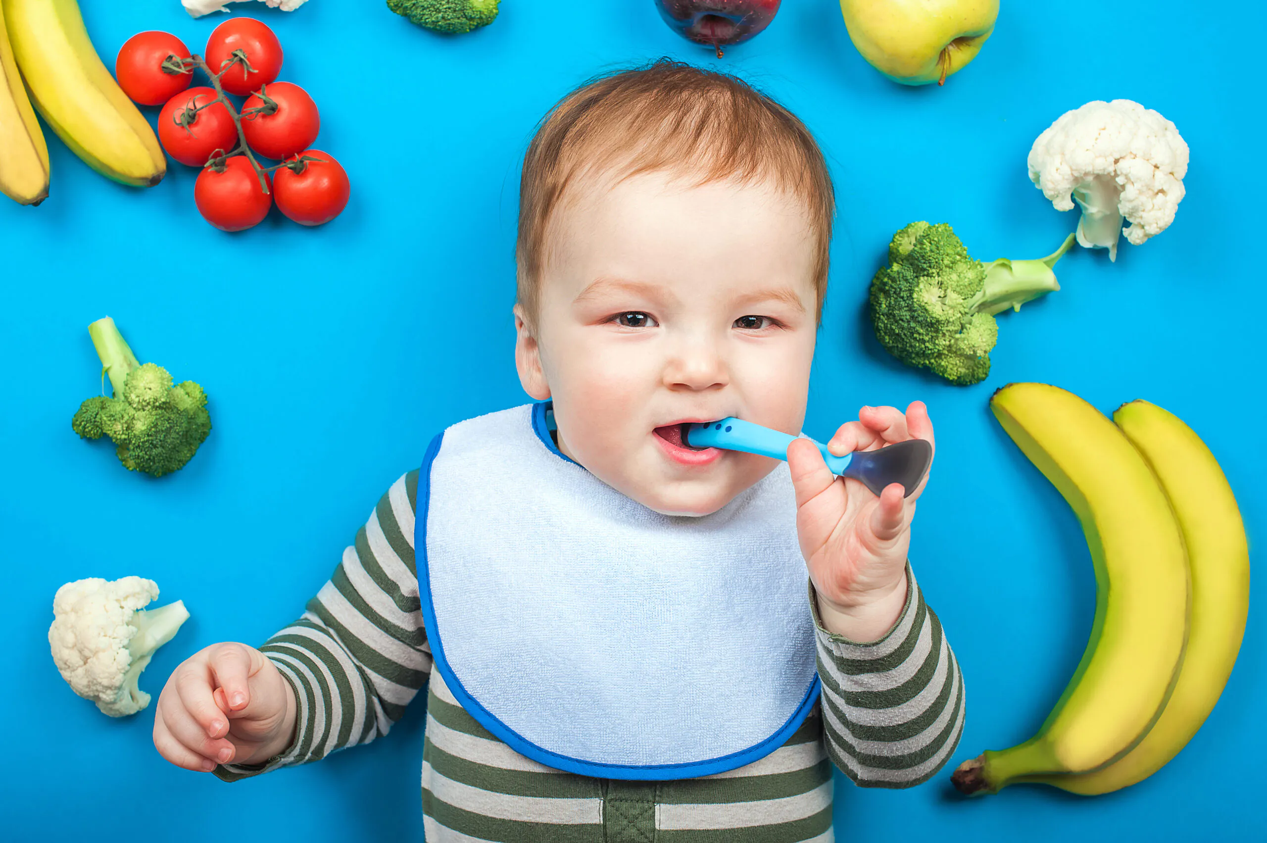 Bebê sorrindo com uma colher na boca, simbolizando a importância da nutrição e cuidados bucais.